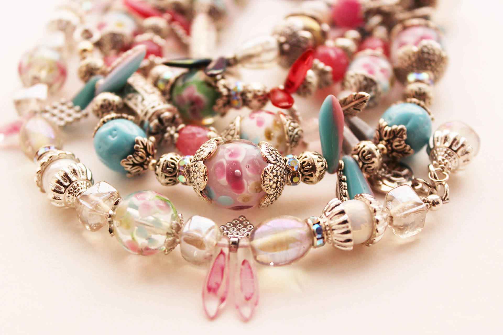 Several glass bead bracelets placed in a curve arrangement on white background