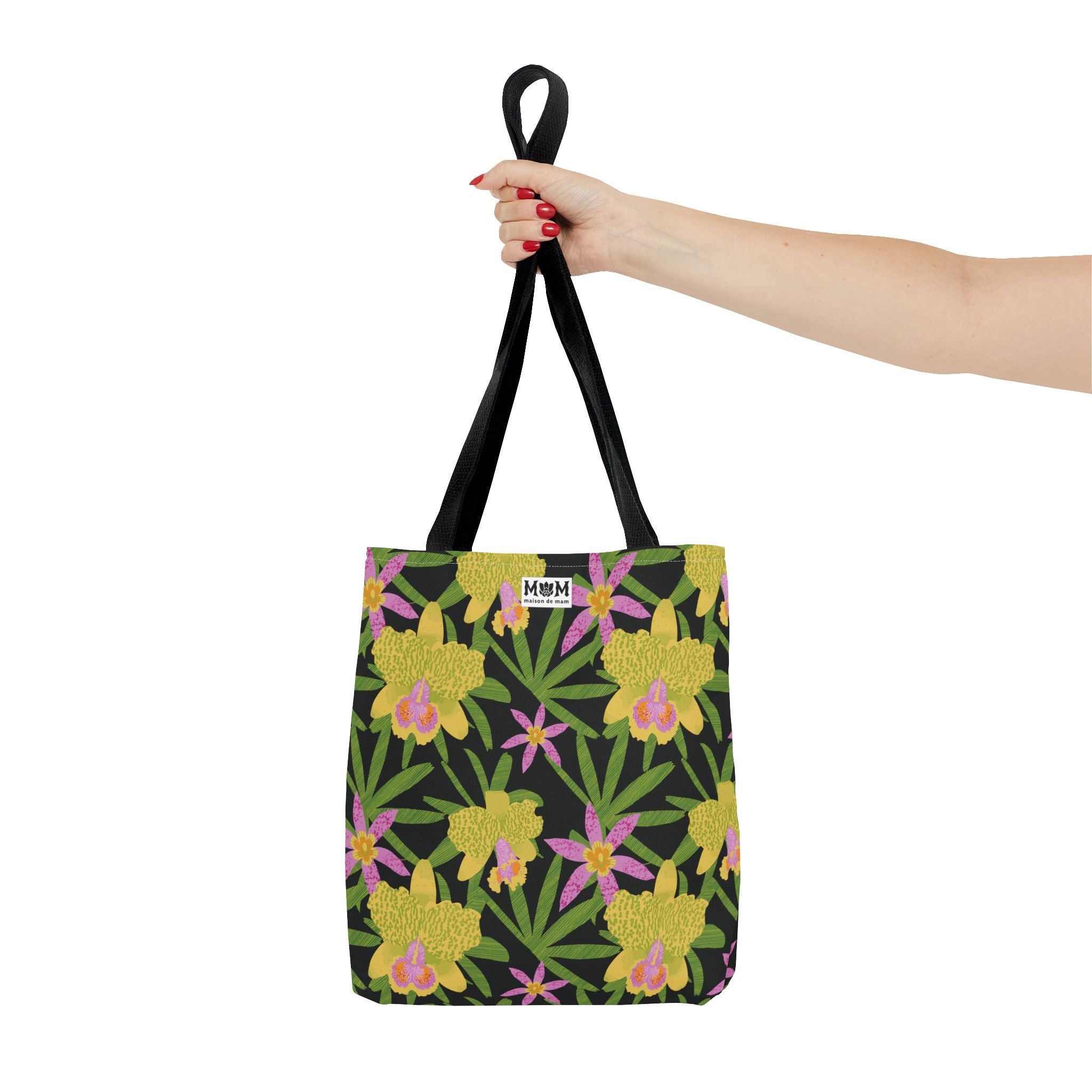 Black tote bag with floral design held by a hand on a white background