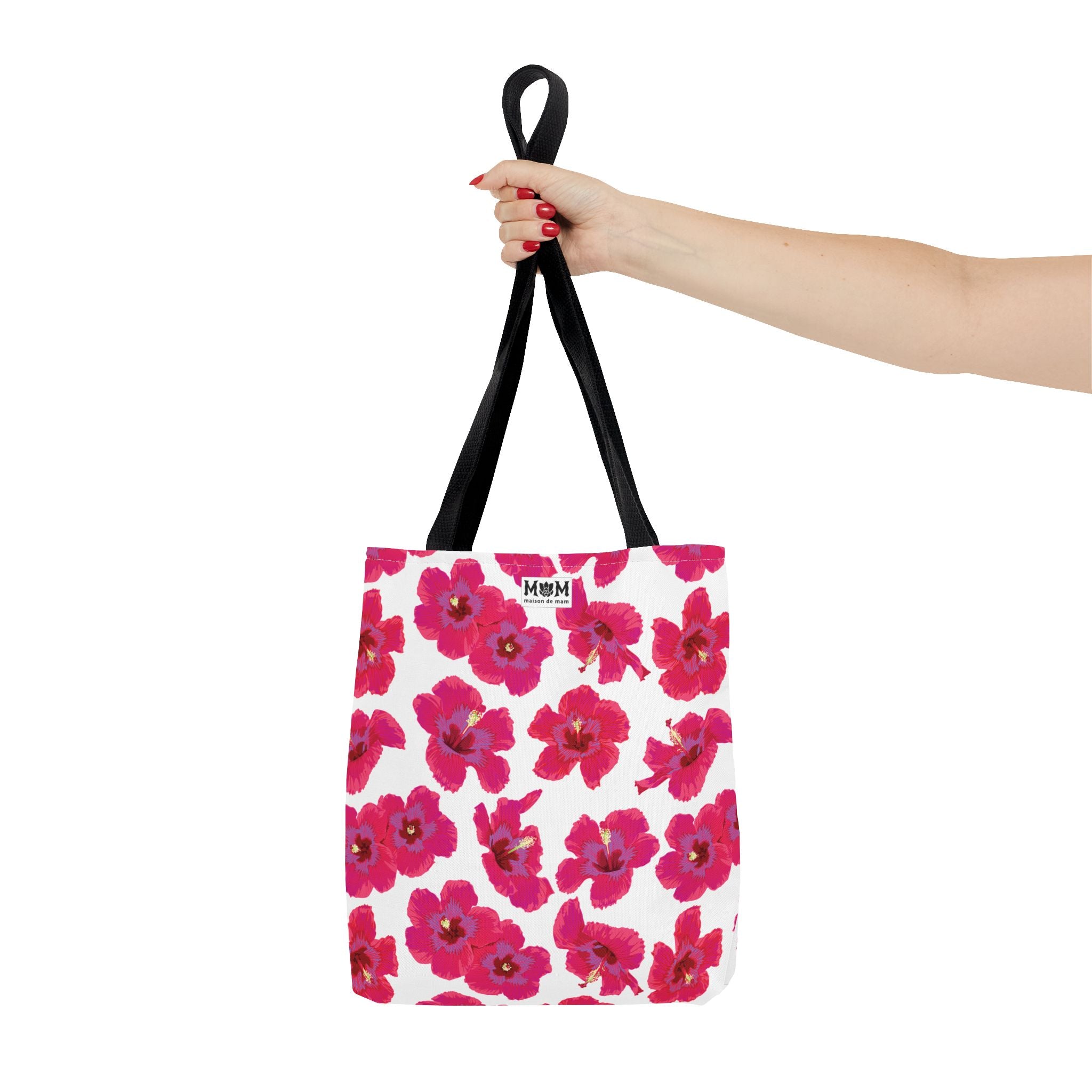 White tote bag with pink floral pattern held by a hand on a white background