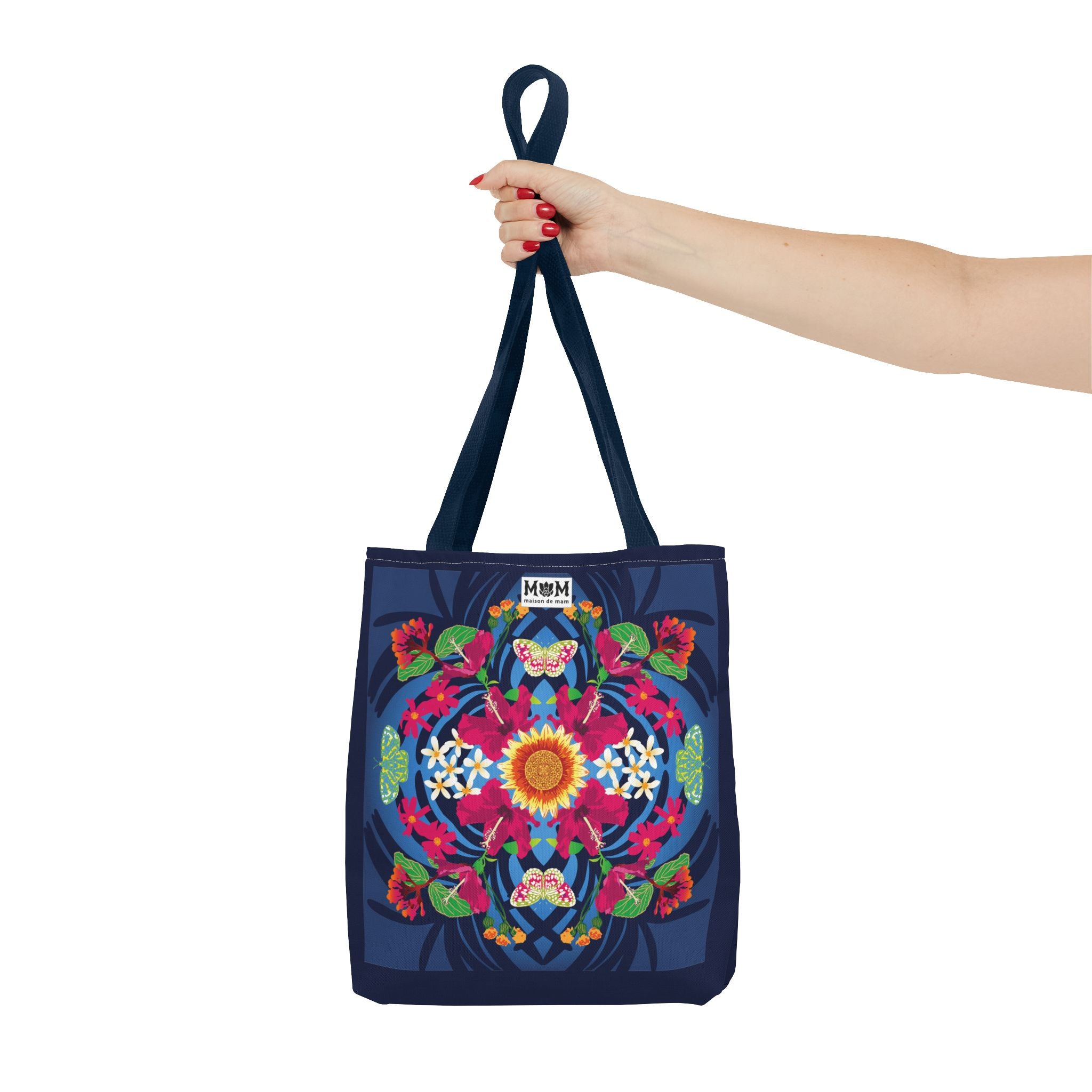 Deep blue tote bag with colorful floral design held by a hand on a white background