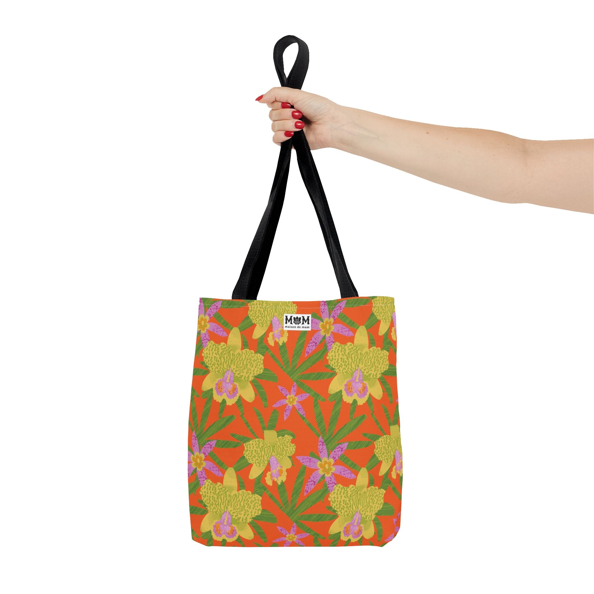 Orange tote bag with floral pattern held by a hand on a white background