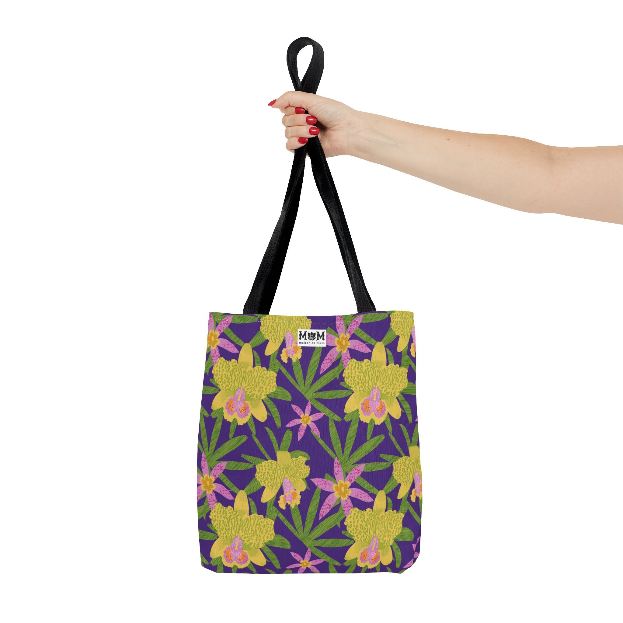 Purple tote bag with floral pattern held by a hand on a white background