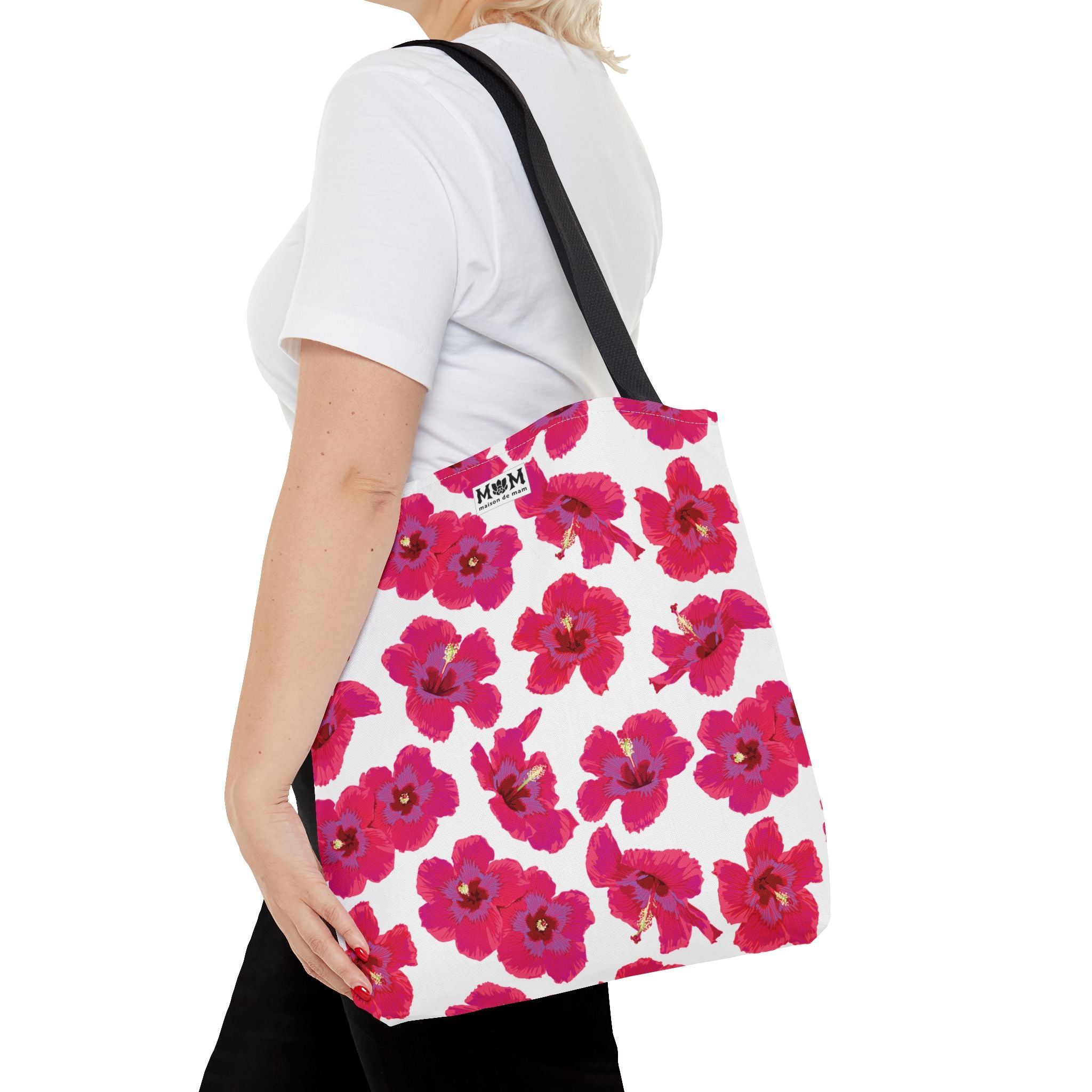 Person wearing a white tote bag with pink floral pattern on a white background