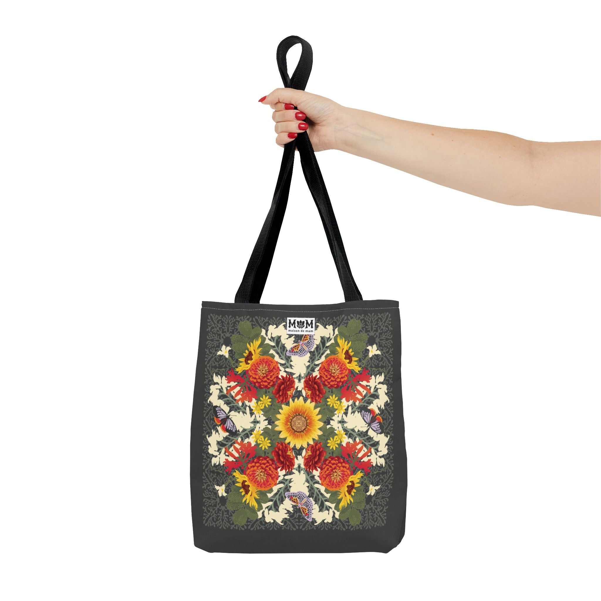Muted green tote bag with floral design held by a hand on a white background