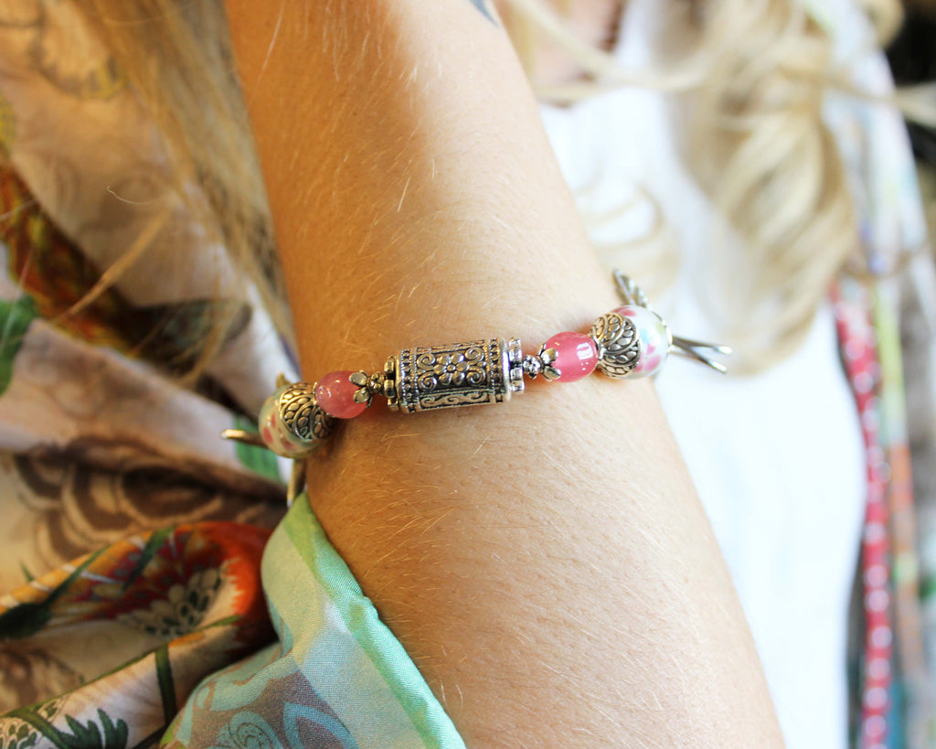 Close-up of a bracelet with pink beads and gold accents on a person's wrist.
