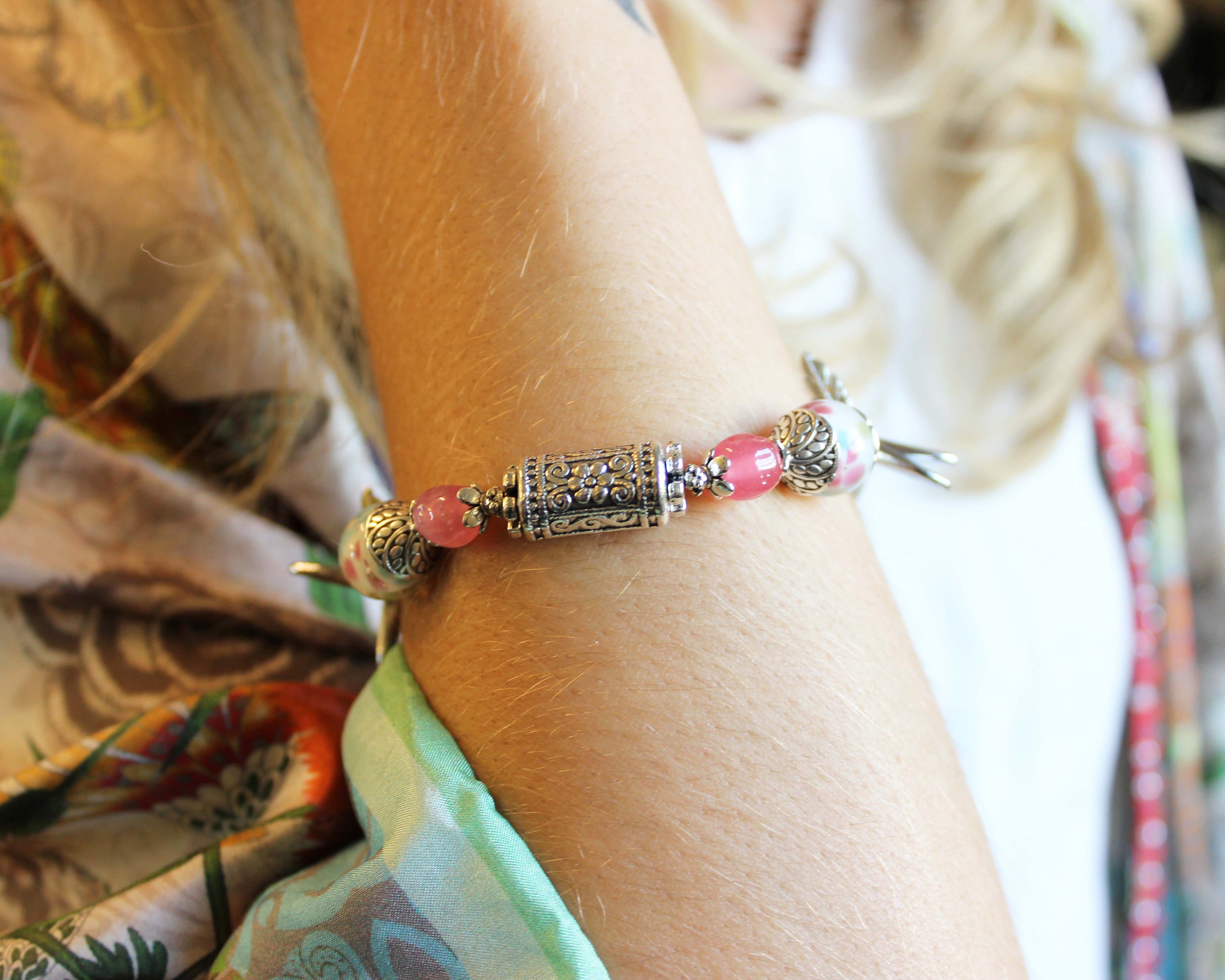 Close-up of a bracelet with pink beads and gold accents on a person's wrist.