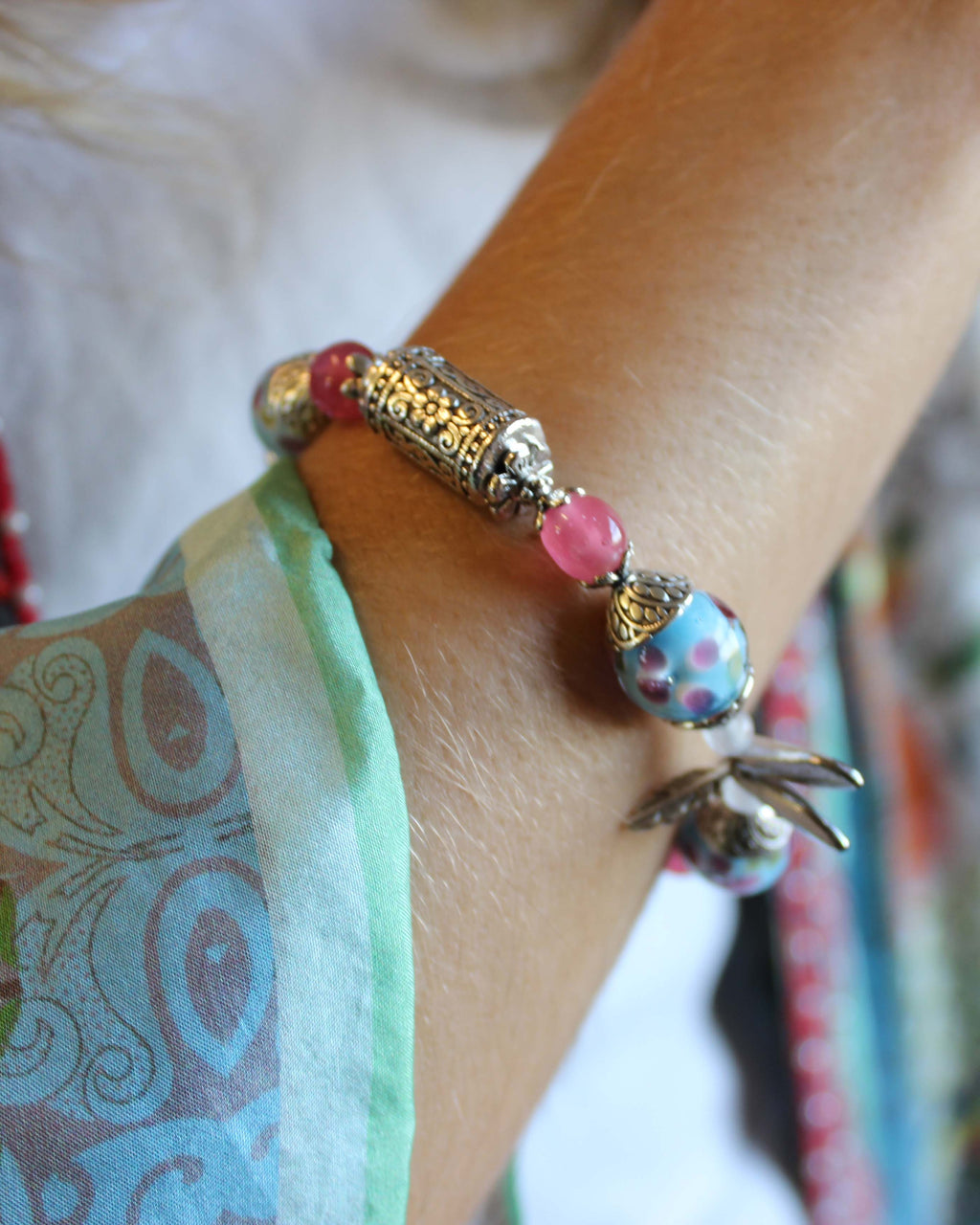 Close-up of a wrist wearing a colorful beaded bracelet with a floral design.