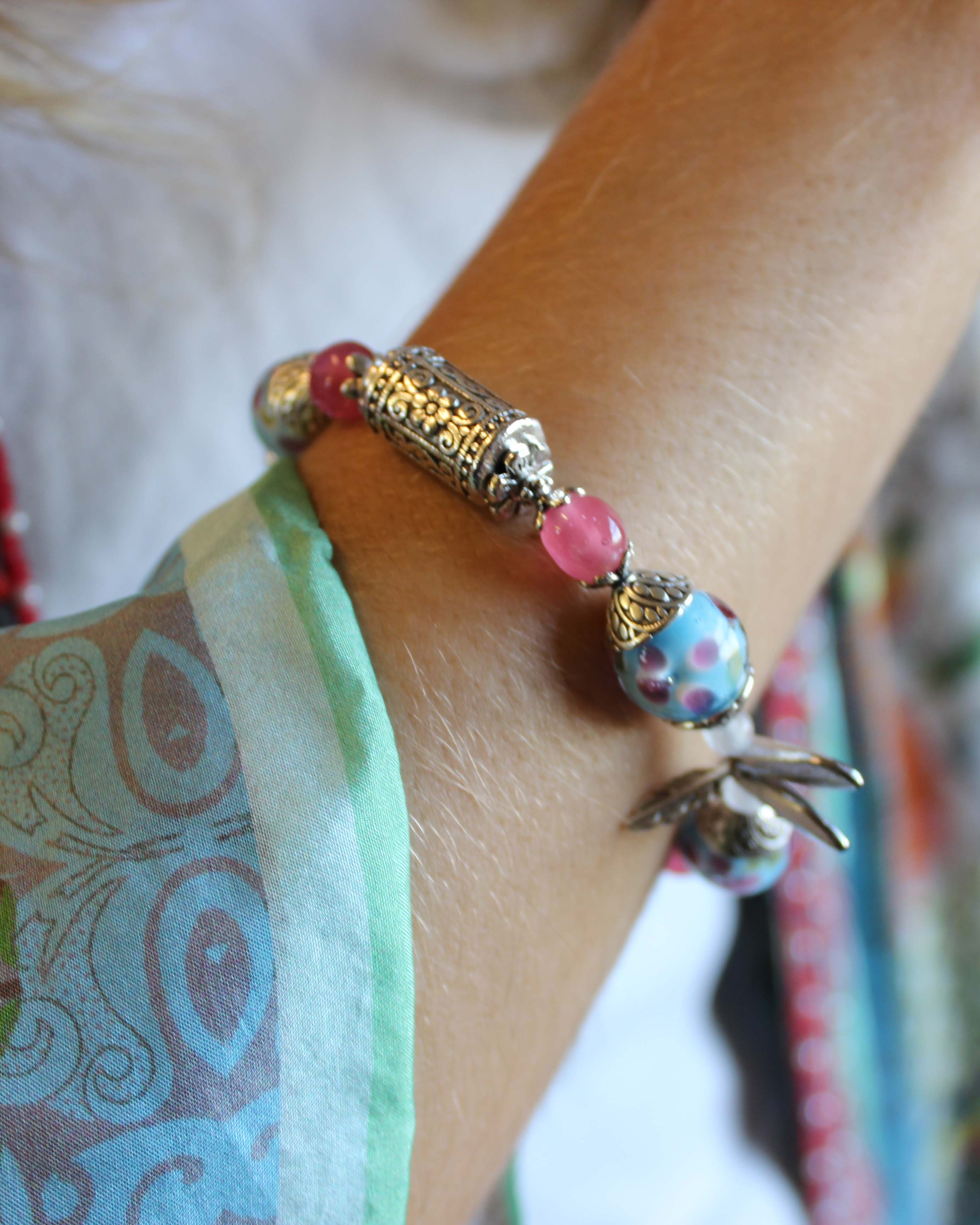 Close-up of a wrist wearing a colorful beaded bracelet with a floral design.