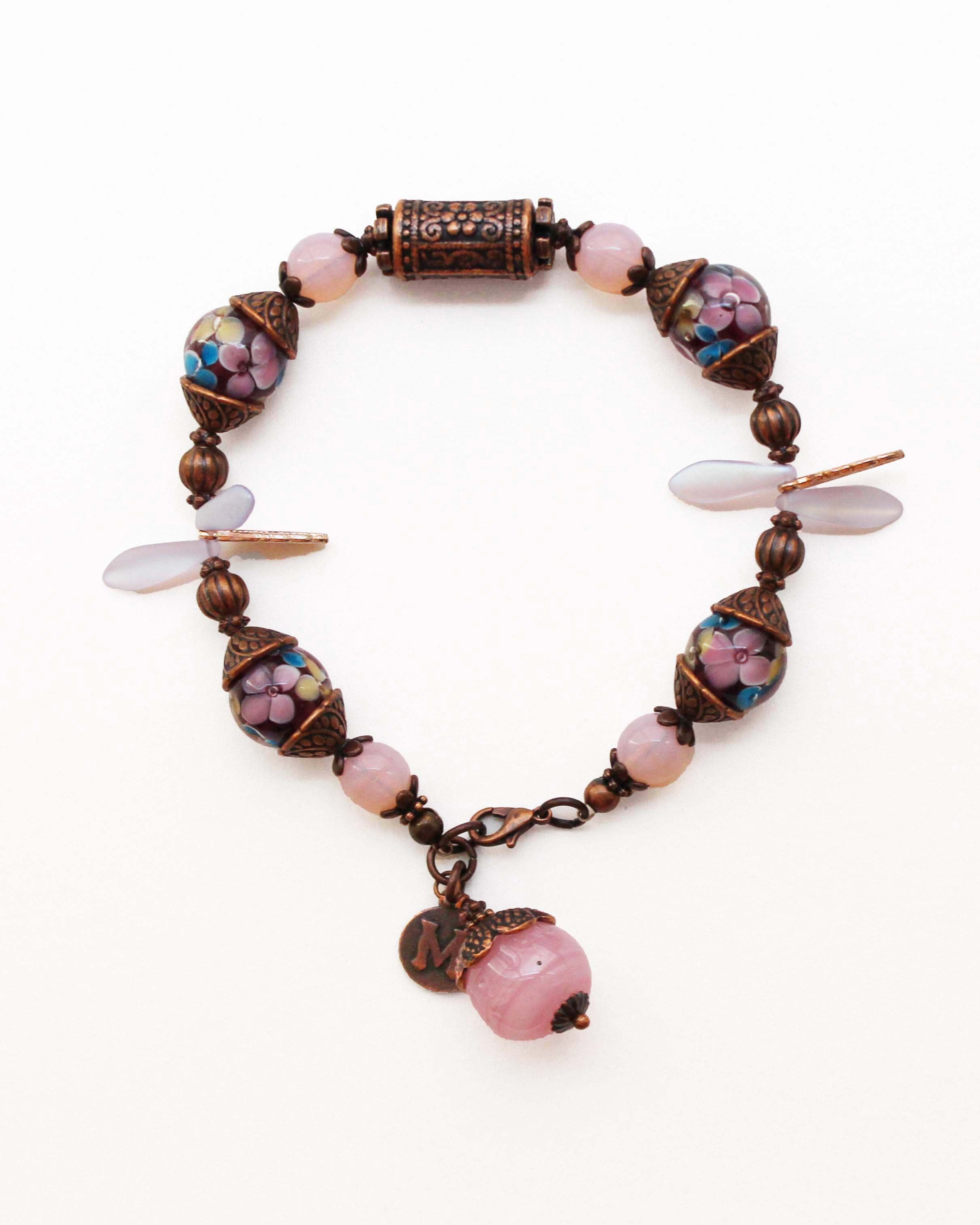 Bracelet with pink beads and floral patterns on a white background