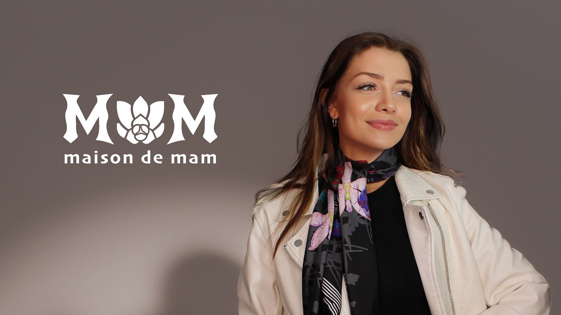 Woman wearing a colorful scarf with 'maison de mam' logo on a dark background